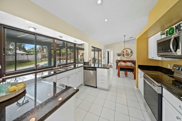 870 SW Gardens Blvd, Palm City, FL 34990 - kitchen featuring vaulted ceiling, a sink, light tile patterned flooring, white cabinetry, and appliances with stainless steel finishes
