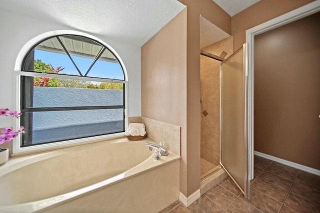 870 SW Gardens Blvd, Palm City, FL 34990 - full bathroom with tile patterned floors, a bath, baseboards, a textured ceiling, and a stall shower