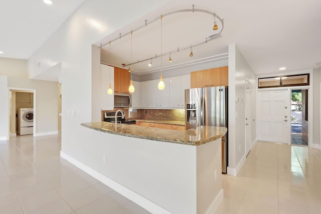 kitchen featuring decorative backsplash, washer / dryer, light stone countertops, appliances with stainless steel finishes, and light tile patterned floors
