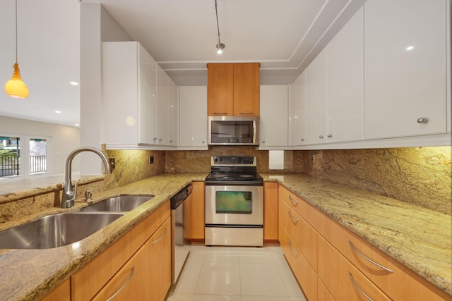 kitchen with white cabinets, appliances with stainless steel finishes, a sink, decorative backsplash, and light tile patterned floors