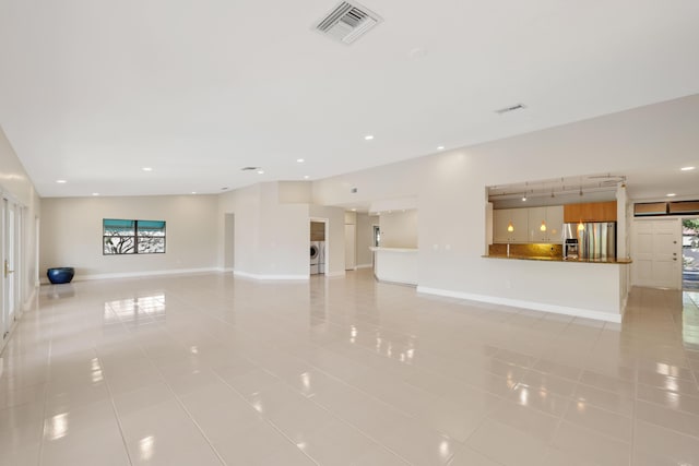unfurnished living room with visible vents, baseboards, separate washer and dryer, light tile patterned floors, and a wealth of natural light