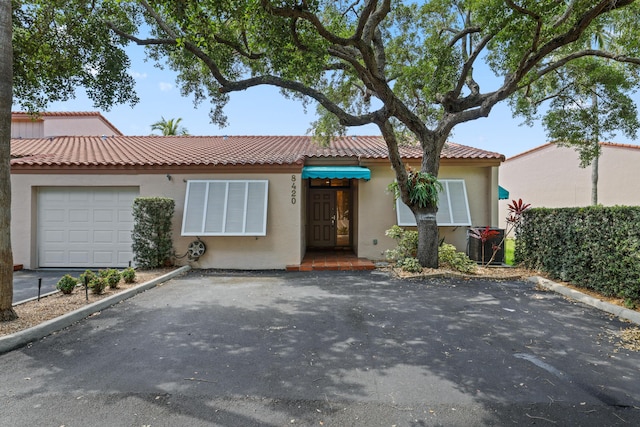 view of front of home featuring an attached garage, aphalt driveway, stucco siding, and a tiled roof