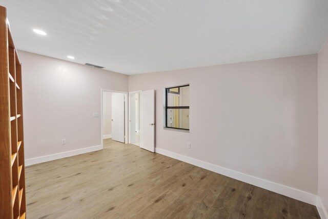 unfurnished room with recessed lighting, baseboards, visible vents, and wood finished floors