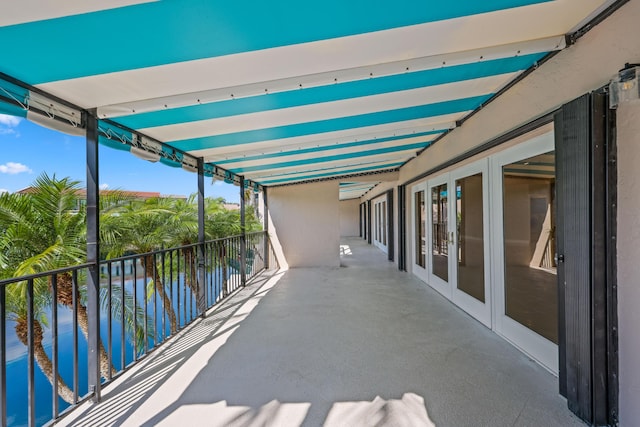 view of patio featuring a water view, french doors, and a balcony