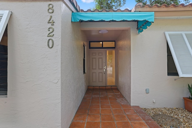 view of exterior entry with stucco siding and a tile roof