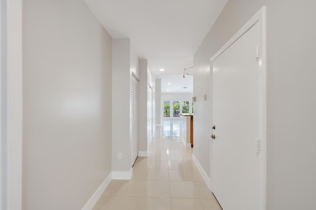 hallway featuring light tile patterned floors, baseboards, and recessed lighting