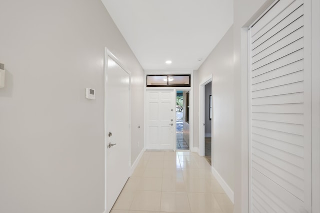hallway featuring baseboards, recessed lighting, and light tile patterned floors