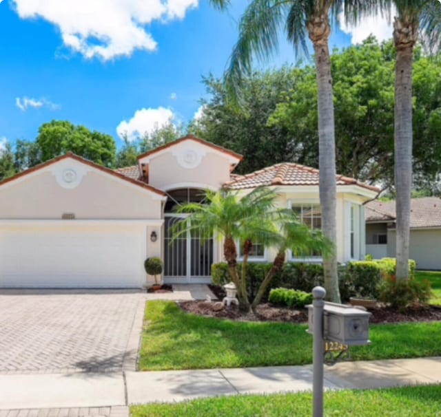 mediterranean / spanish home with stucco siding, a tiled roof, driveway, and a garage