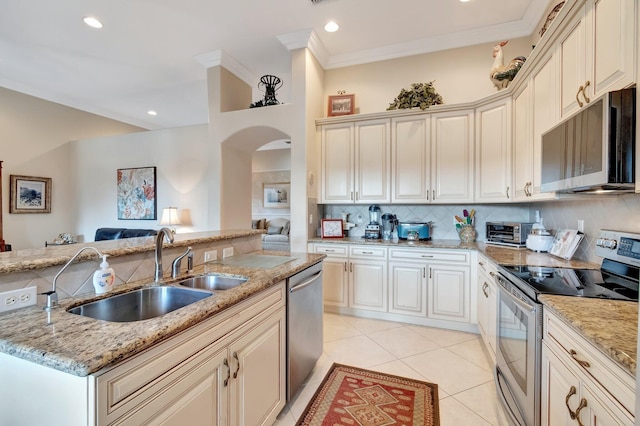 kitchen featuring a sink, decorative backsplash, open floor plan, arched walkways, and appliances with stainless steel finishes