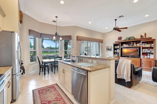 kitchen featuring a sink, light tile patterned flooring, appliances with stainless steel finishes, cream cabinets, and ceiling fan with notable chandelier