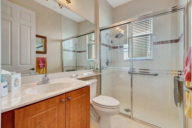 bathroom with tile patterned floors, vanity, a shower stall, and toilet