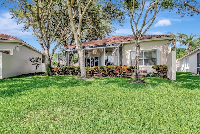 view of front of property with a ceiling fan, a tiled roof, a front lawn, and stucco siding