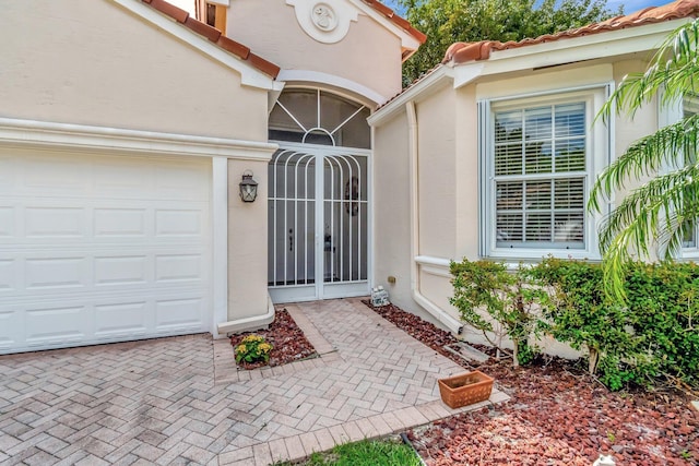 view of exterior entry featuring an attached garage and stucco siding