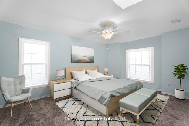 carpeted bedroom featuring baseboards, ceiling fan, visible vents, and a skylight