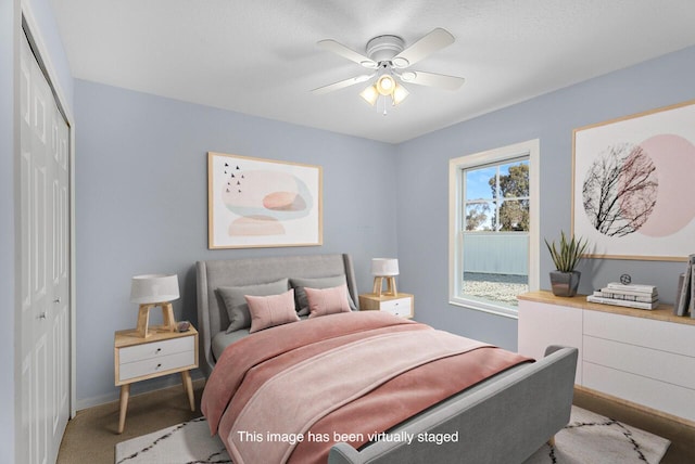 bedroom featuring light colored carpet, a closet, baseboards, and a ceiling fan