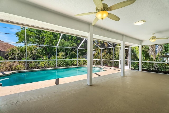 outdoor pool featuring a patio, a ceiling fan, and glass enclosure