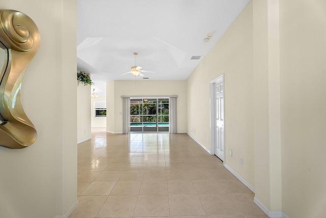 corridor featuring a high ceiling, light tile patterned floors, baseboards, and visible vents