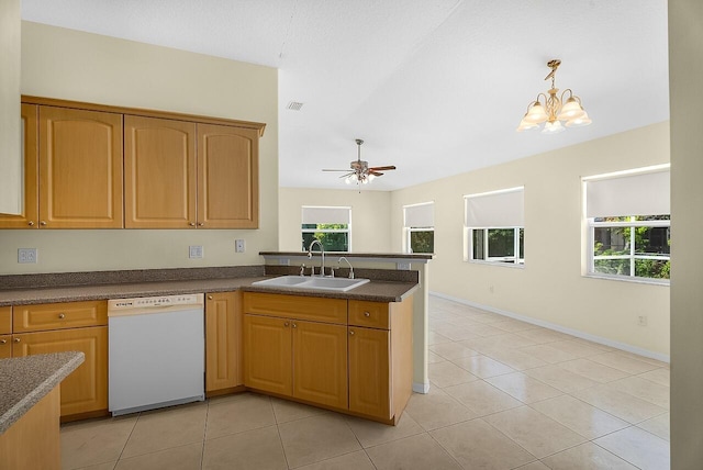 kitchen with a peninsula, dark countertops, a sink, white dishwasher, and light tile patterned floors