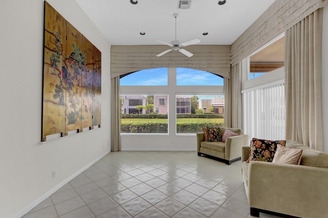 interior space featuring light tile patterned flooring, visible vents, baseboards, a towering ceiling, and a ceiling fan