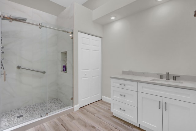 bathroom with vanity, a stall shower, and wood finished floors