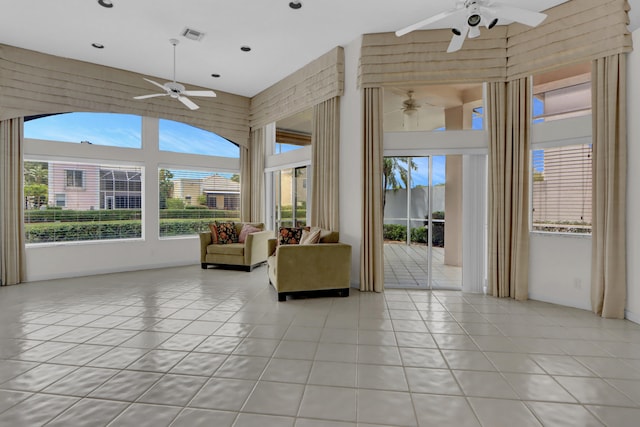 unfurnished living room featuring a high ceiling, a ceiling fan, plenty of natural light, and light tile patterned floors