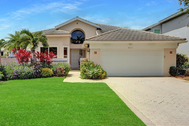 view of front of house with a front lawn, decorative driveway, stucco siding, and an attached garage