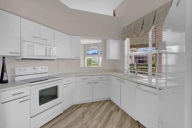 kitchen featuring light countertops, light wood-style flooring, white appliances, white cabinetry, and a sink