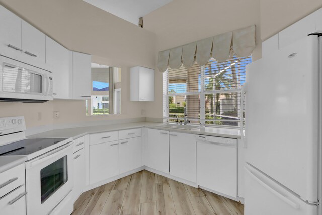 kitchen with light countertops, a sink, white cabinetry, light wood-type flooring, and white appliances