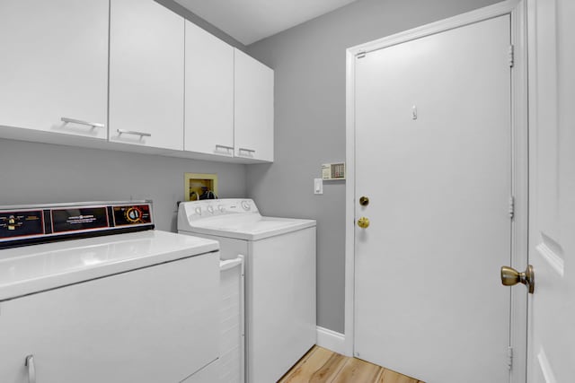 washroom with washing machine and clothes dryer, cabinet space, and light wood-type flooring