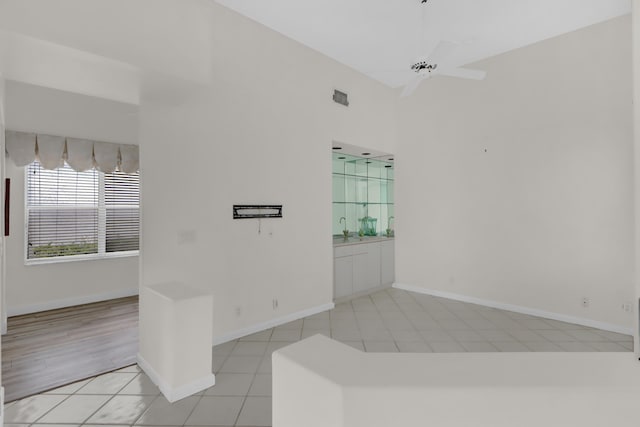 tiled empty room with baseboards, ceiling fan, and a sink