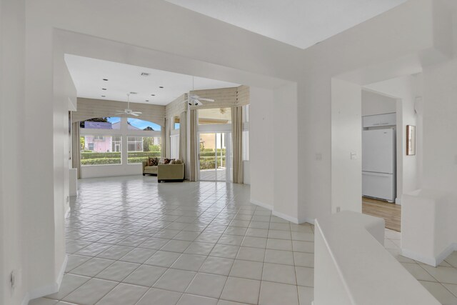 unfurnished room featuring baseboards, ceiling fan, and light tile patterned floors