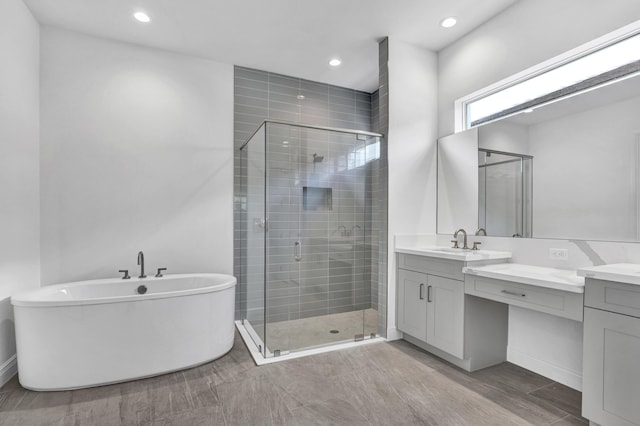 130 SE Palma St, Port Saint Lucie, FL 34984 - bathroom with vanity, a stall shower, a freestanding tub, recessed lighting, and wood finished floors
