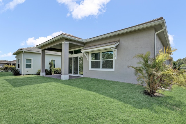 130 SE Palma St, Port Saint Lucie, FL 34984 - rear view of house featuring stucco siding and a yard