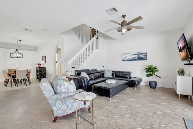 living area featuring light tile patterned flooring, arched walkways, stairs, and visible vents