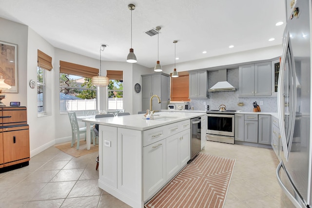 kitchen featuring gray cabinetry, wall chimney range hood, a sink, and appliances with stainless steel finishes