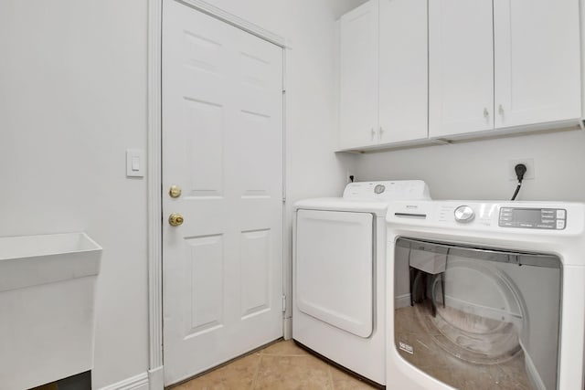 clothes washing area featuring independent washer and dryer, light tile patterned flooring, and cabinet space