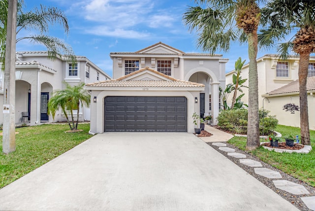 mediterranean / spanish-style house with an attached garage, a front yard, stucco siding, a tile roof, and driveway
