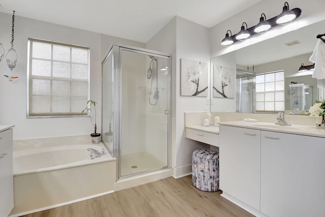 bathroom featuring vanity, a shower stall, a garden tub, visible vents, and wood finished floors