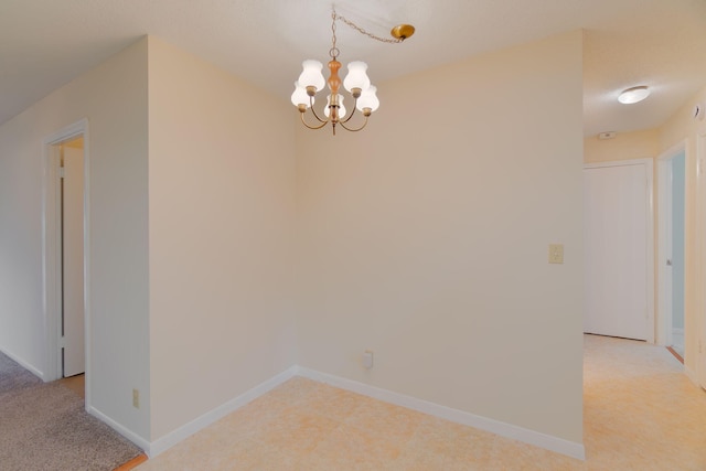 unfurnished dining area featuring light carpet, baseboards, and an inviting chandelier