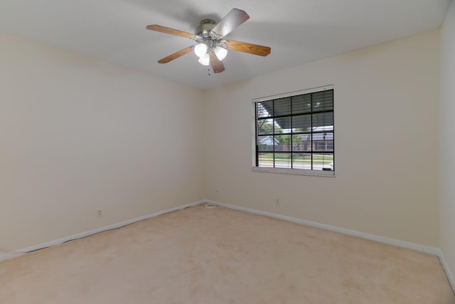 spare room with ceiling fan, baseboards, and light carpet