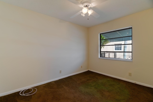 unfurnished room featuring dark colored carpet, baseboards, and ceiling fan