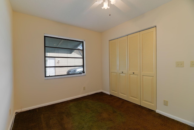 unfurnished bedroom with dark carpet, ceiling fan, baseboards, and a closet