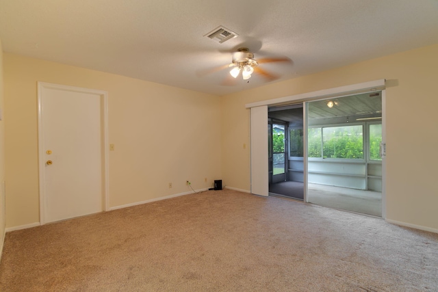 carpeted spare room with visible vents, a ceiling fan, and baseboards
