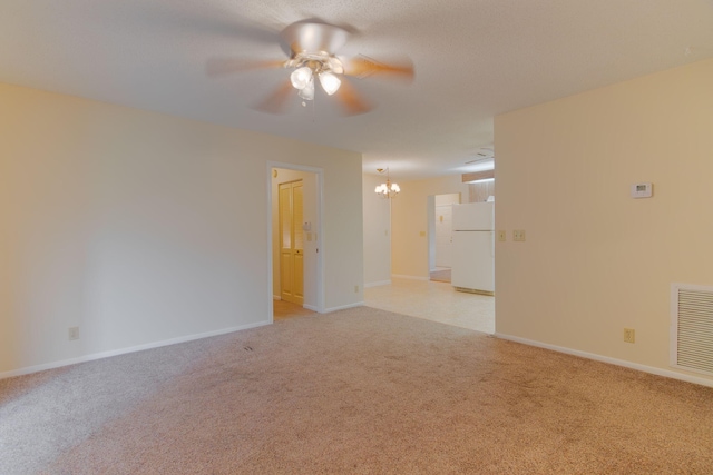 empty room with light colored carpet, baseboards, visible vents, and ceiling fan with notable chandelier