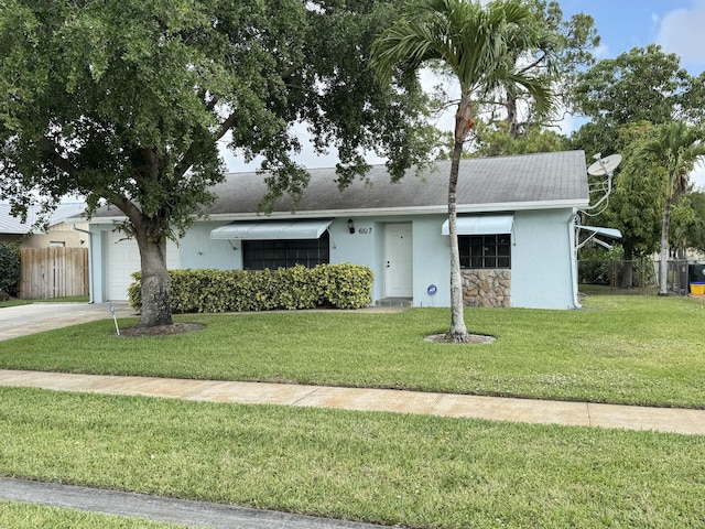 view of front of house featuring an attached garage, a front lawn, stucco siding, and fence