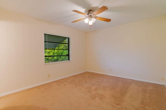unfurnished room with ceiling fan, baseboards, and light carpet
