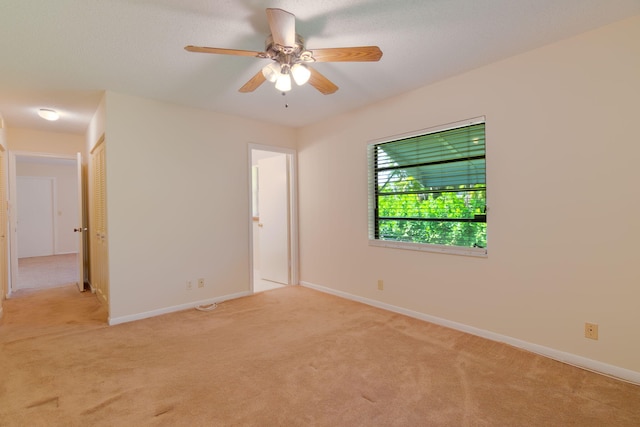 spare room with ceiling fan, baseboards, and light carpet