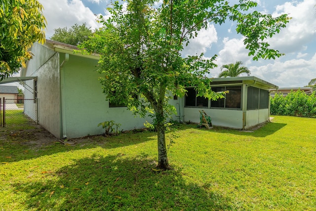 back of house featuring fence, a lawn, a sunroom, and stucco siding