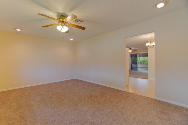 empty room featuring baseboards, visible vents, recessed lighting, light colored carpet, and ceiling fan with notable chandelier
