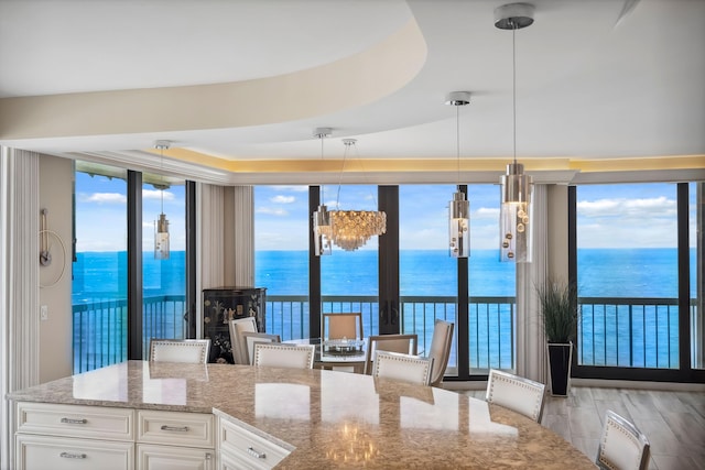 9900 S Ocean Dr Unit 1601, Jensen Beach, FL 34957 - kitchen with a water view, decorative light fixtures, light stone countertops, expansive windows, and white cabinetry